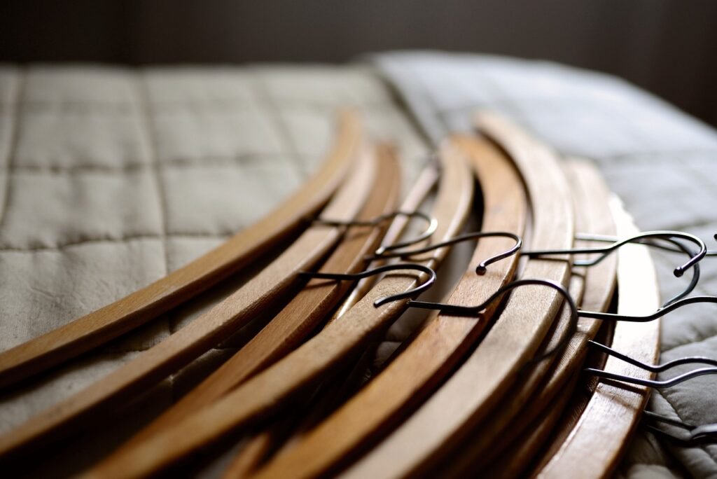 A pile of wooden hangers on a bed, symbolizing eco-friendly and organized wardrobe practices.