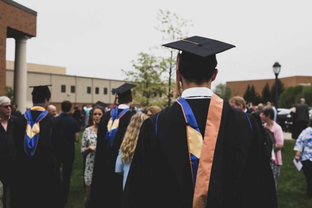 College graduates in caps and gowns celebrating outdoors on graduation day.