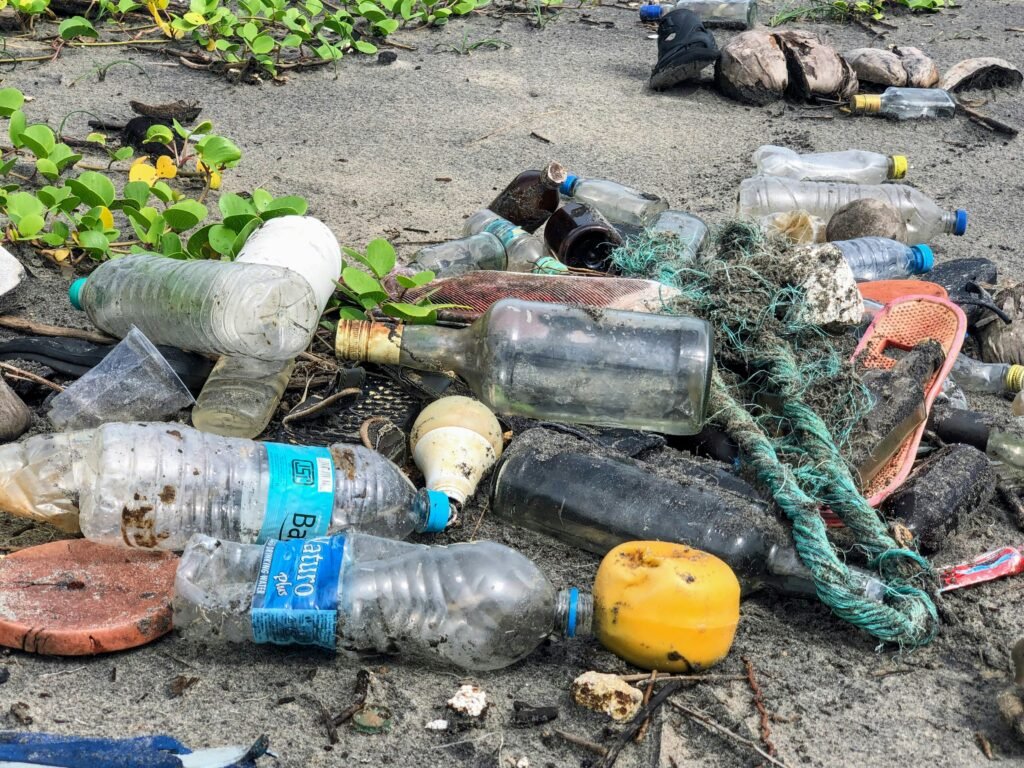 Plastic bottles, ropes, and other waste littering a beach, highlighting the impact of plastic pollution.