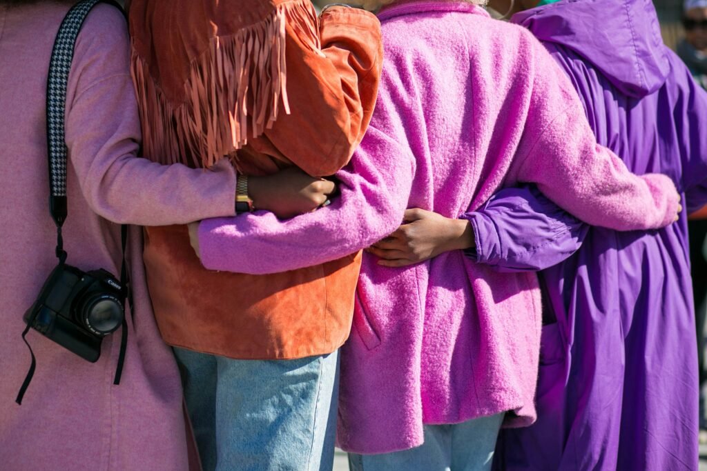 A group of people in colorful coats hugging, symbolizing community and collaboration.